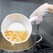 A person using a Vollrath aluminum dipper to pour soup into a pot.