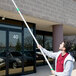 A person using an Unger T4180 Plus extension pole outside a building.