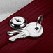 A silver key on a key ring on a wooden table next to a Cherry Finish Aarco Lighted Bulletin Board Cabinet key.