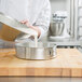 A person pouring a mixture from a silver bowl into a Chicago Metallic Springform cake pan.