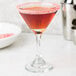 A martini glass with a red rim and a Rokz Triple Berry cocktail garnish.
