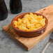 A Libbey terracotta cazuela bowl filled with macaroni and cheese on a table.