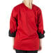 A woman wearing a red Mercer Culinary chef jacket with black pants.