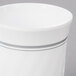 A close up of a white plastic coffee cup with silver accents.