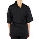 A woman wearing a black Mercer Culinary Millennia Air chef jacket with a full mesh back.