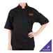 A woman wearing a Mercer Culinary black chef coat with a full mesh back.