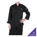 A man wearing a black Mercer Culinary Millennia long sleeve chef jacket with his hands on his hips.