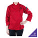 A woman wearing a red Mercer Culinary long sleeve chef jacket.