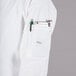 A person wearing a Mercer Culinary white long sleeve cook jacket with a phone and pen in the pocket.