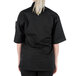 A woman wearing a Mercer Culinary black chef jacket with cloth knot buttons.