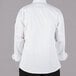 A person wearing a white Mercer Culinary Millennia long sleeve cook jacket with black buttons.
