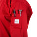 A person wearing a Mercer Culinary Millennia red cook jacket with a pen in the pocket.