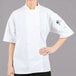A woman wearing a white Mercer Culinary Millennia Air chef jacket.