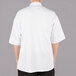 A man wearing a Mercer Culinary Millennia Air short sleeve cook jacket with a full mesh back.