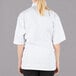 A woman wearing a white Mercer Culinary cook jacket with cloth knot buttons.