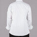 A person wearing a Mercer Culinary white long sleeve chef jacket with black buttons.