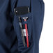 A person's navy Mercer Culinary Millennia chef coat pocket with a phone and pens.
