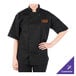 A person wearing a black Mercer Culinary chef coat with an orange logo.