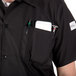 A man wearing a black Mercer Culinary Millennia cook shirt with a phone pocket.