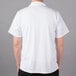 A man wearing a white Mercer Culinary Millennia cook shirt with a mesh back.