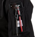 A Mercer Culinary Millennia women's black chef coat with a cell phone and pen in a pocket.