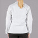 A woman wearing a white Mercer Culinary Millennia long sleeve chef jacket.