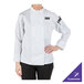 A woman wearing a white Mercer Culinary long sleeve chef jacket.