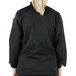 A woman wearing a Mercer Culinary Millennia black long sleeve chef jacket.