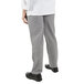 The lower half of a person wearing Mercer Culinary Millennia women's houndstooth chef pants and black shoes.