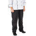 A person wearing Mercer Culinary black pinstripe cook pants in a professional kitchen.