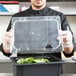 A person holding a clear plastic container with a clear lid.