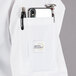A white Mercer Culinary Millennia short sleeve cook jacket with a pocket and pen.