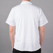 A man wearing a white Mercer Culinary Millennia cook shirt with a full mesh back.