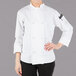 A woman wearing a white Mercer Culinary long sleeve chef jacket with knot buttons.