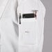 A person wearing a Mercer Culinary Millennia white chef coat with a phone and pen in the pocket.