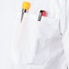 A pocket of a white Mercer Culinary Millennia cook shirt with a pen and a yellow object in it.