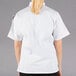 A woman wearing a white Mercer Culinary short sleeve chef jacket.