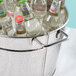 A hammered metal beverage tub filled with bottles of water on a table in a cocktail bar.