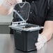 A person in gloves holding a Carlisle Clear Polycarbonate food pan lid over a black container.