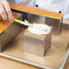 A person frosting a cake with a Matfer Bourgeat square metal cake frame.