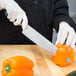 A person using a Mercer Renaissance chef's knife to cut a bell pepper.