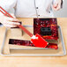 A woman using a Matfer Bourgeat cake frame to cut a cake.