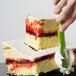 A hand using a green spatula to cut a wedding cake using a Matfer Bourgeat deconstructed cake frame.