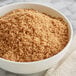 A bowl of dark brown sugar on a table.