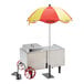 A small stainless steel hot dog cart with red wheels and a red and yellow umbrella labeled 'HOTDOGS.'
