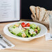 A bowl of salad with tomatoes and croutons on a table with a glass of water.