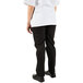 The legs of a person wearing Mercer Culinary black chef trousers and a white shirt.