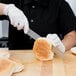 A person cutting a sandwich with a Mercer Culinary Renaissance bread knife.