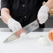 A person in gloves cutting a white onion with a Victorinox chef knife.
