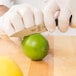 A person in white gloves using a Mercer Culinary Z&#252;M Forged Paring Knife to cut a lime.